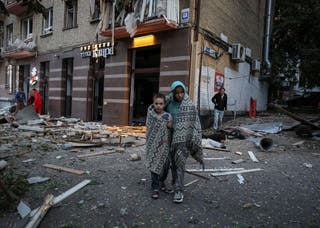 Residents look on at the site of an apartment building hit during Russian drone and missile strikes in Kyiv